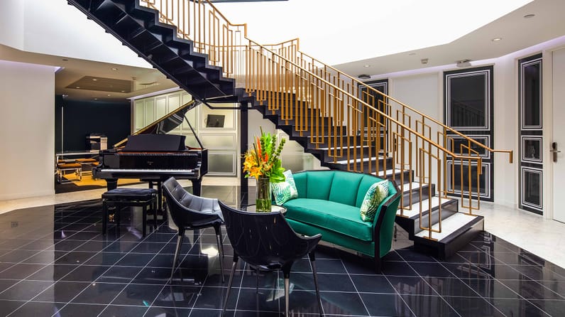 10 Brick Street's staircase, grand piano and plush green sofa